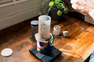 Kettle pouring water into an AeroPress filled with freshly ground coffee