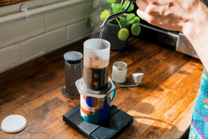 Image of kettle pouring hot wated into an AeroPress placed on a mug on a set of weighing scales