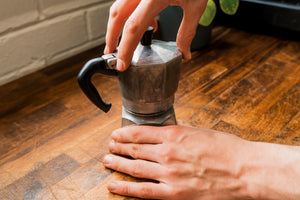 Close up of mans hands screwing a silver Mokapot together