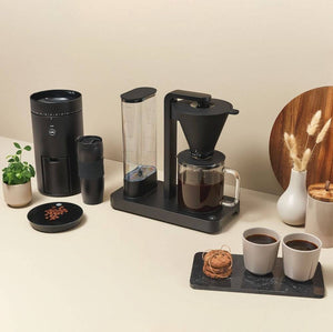 Lifestyle image of a Wilfa Coffee Maker a Coffee Grinder and two white cups filled with black coffee