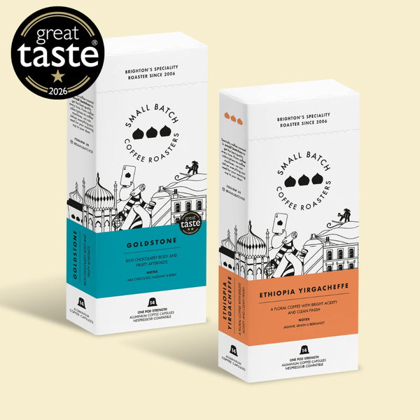 Two coffee roaster boxes from Small Batch Coffee Roasters on a light beige background, with a Great Taste 2026 award badge in the top-left corner. The left box is labeled Goldstone with a turquoise band, and the right box is labeled Ethiopia Yirgacheffe with an orange band.
