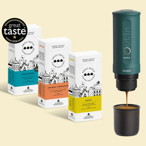 Three boxes of Small Batch Coffee Roastery beans in different flavors (Colombstone, Ethiopia Yirgachee, and Decaf) are shown alongside a dark teal Dublin portable espresso maker dispensing coffee into a black cup, with a 'great taste 2023' award badge in the top left corner.