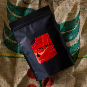 Black coffee bag with a red label on a burlap background with coffee bean design