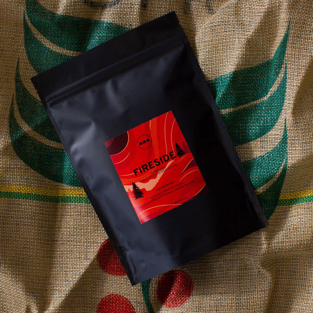fireside coffee. Black coffee bag with a red label on a textured fabric background