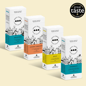 Four boxes of Small Batch Coffee Roasters in different flavors and roast levels, arranged diagonally on a light beige background with a 'great taste 2023' award badge in the top right corner.